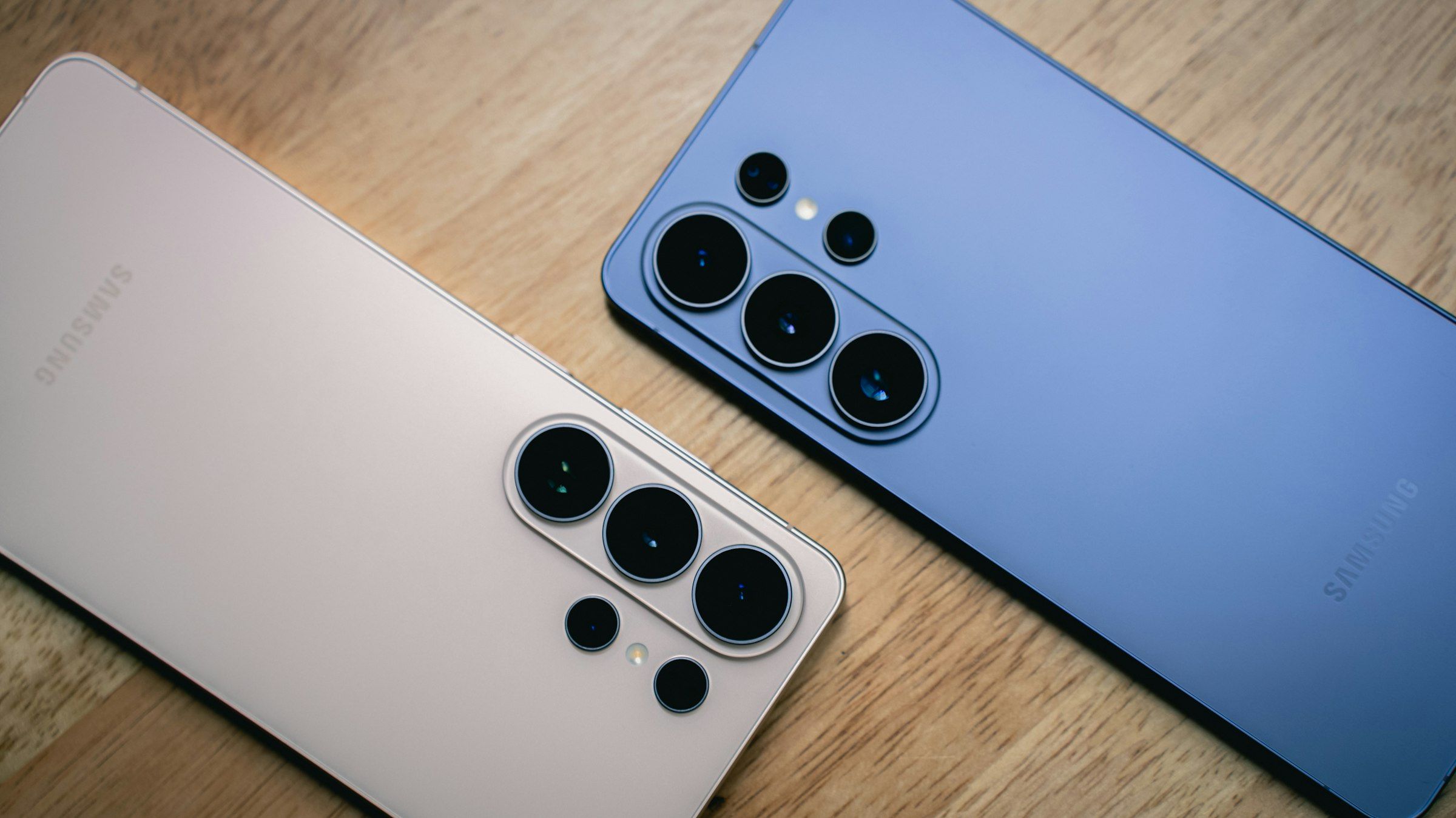 Two Samsung Galaxy phones lying face down on a wooden table