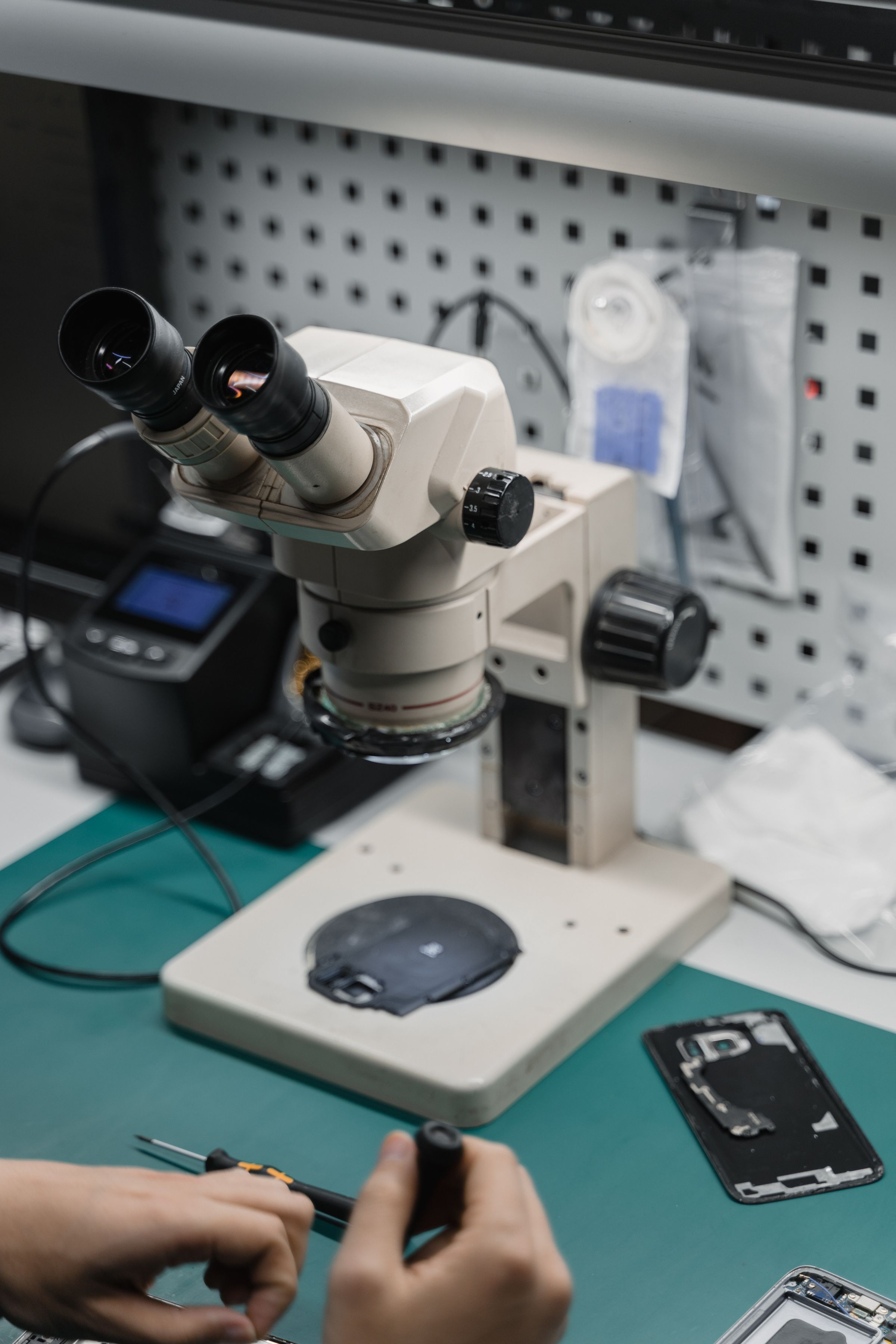 Repair bench with a microscope and a disassembled iPhone