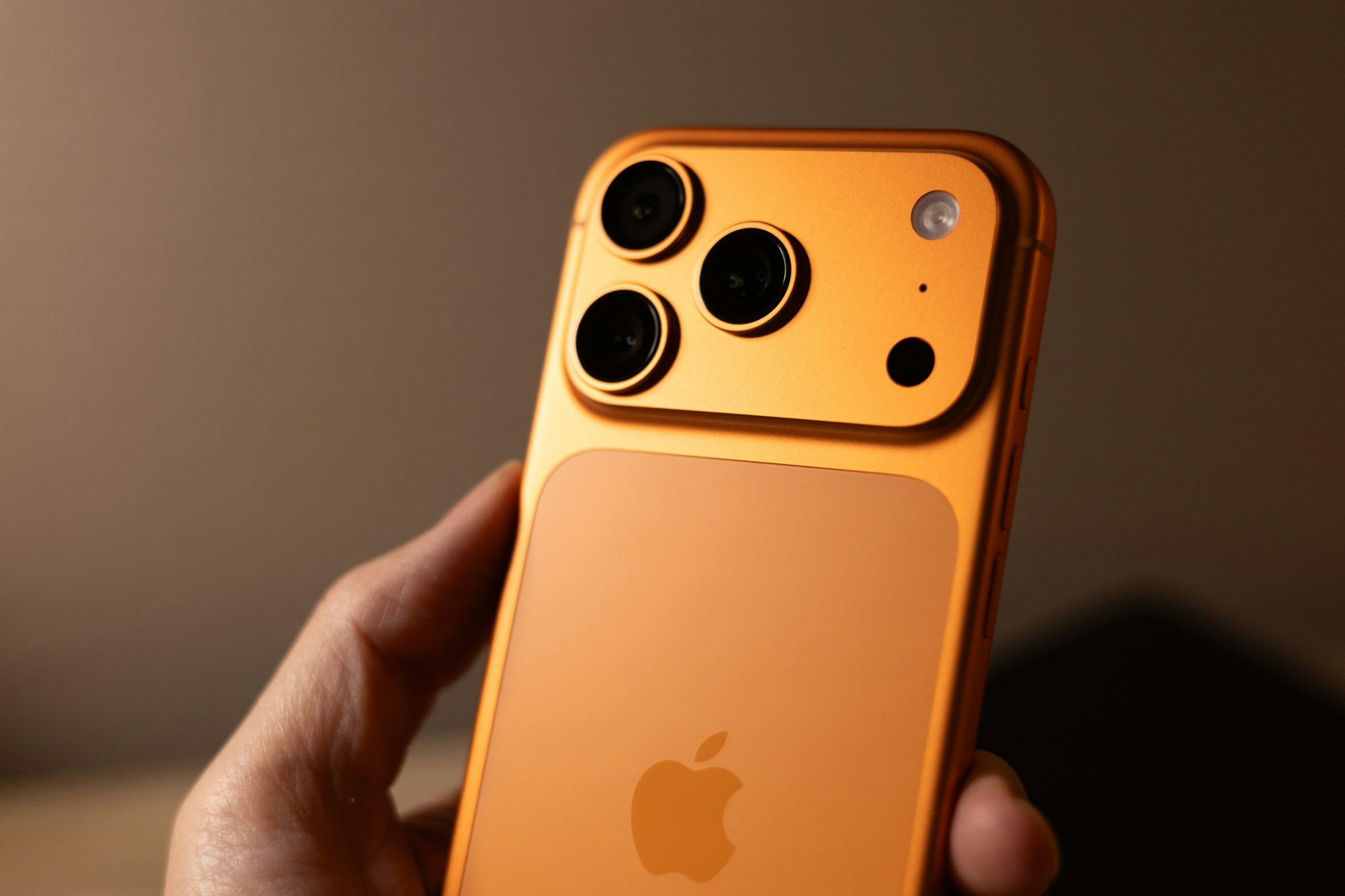 Hand holding an orange iPhone
