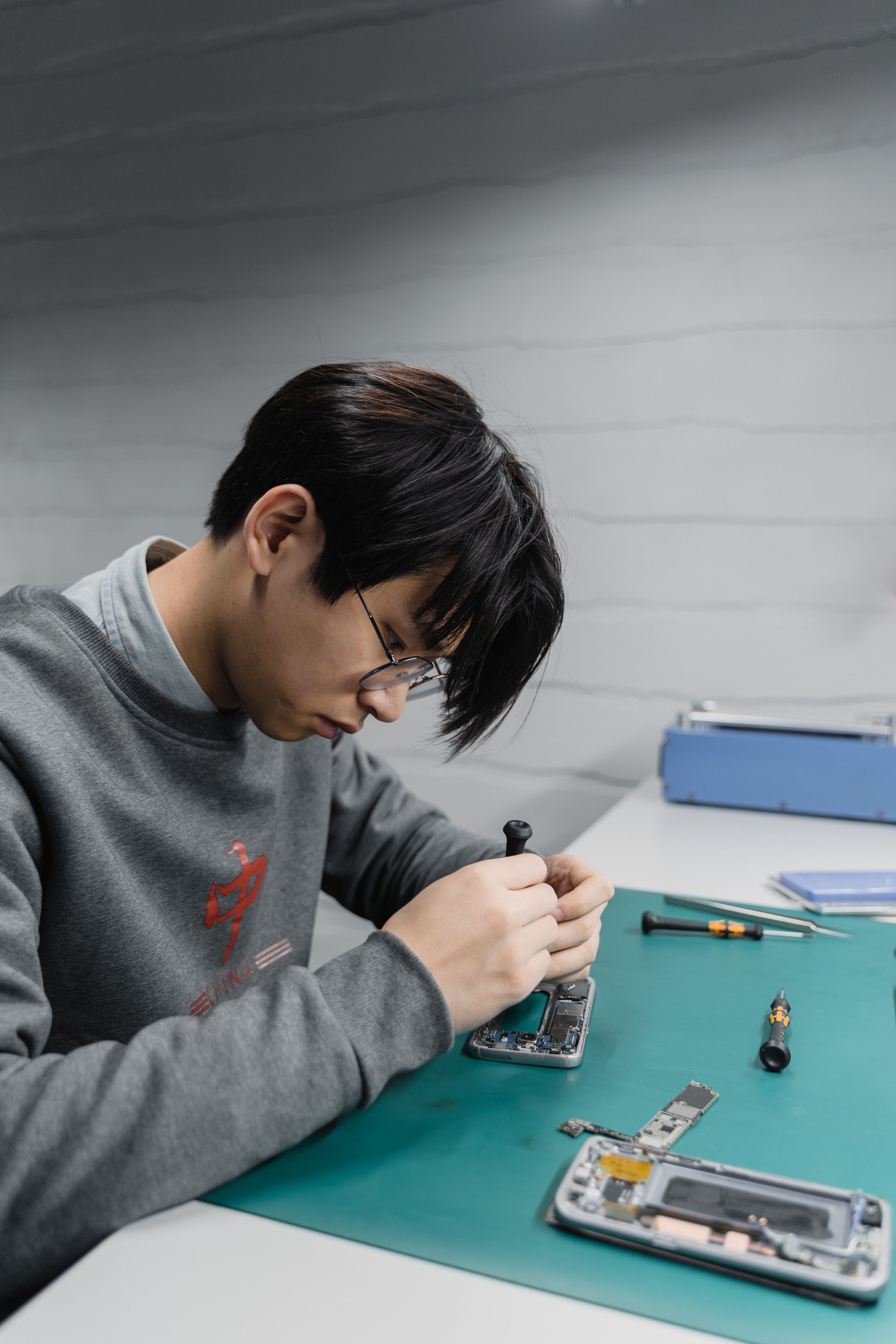 Technician repairing a disassembled Samsung phone at a workbench
